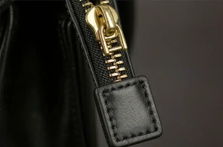 zipper tape and pull running across black leather, photographed close