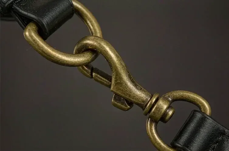 antique brass snap hook and ring mounted on a leather strap